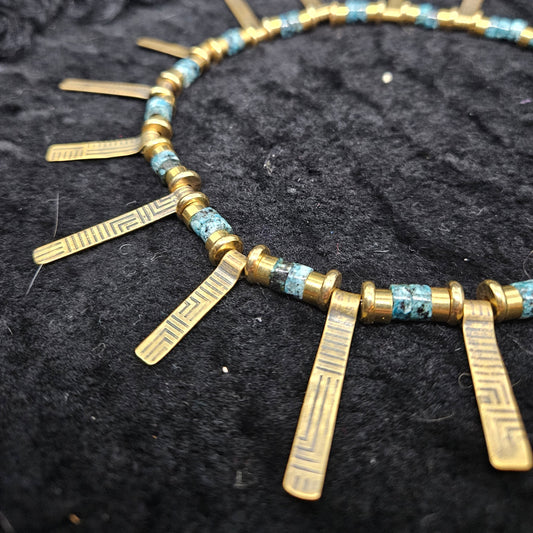 Necklace with gold and blue beads on a textured black background