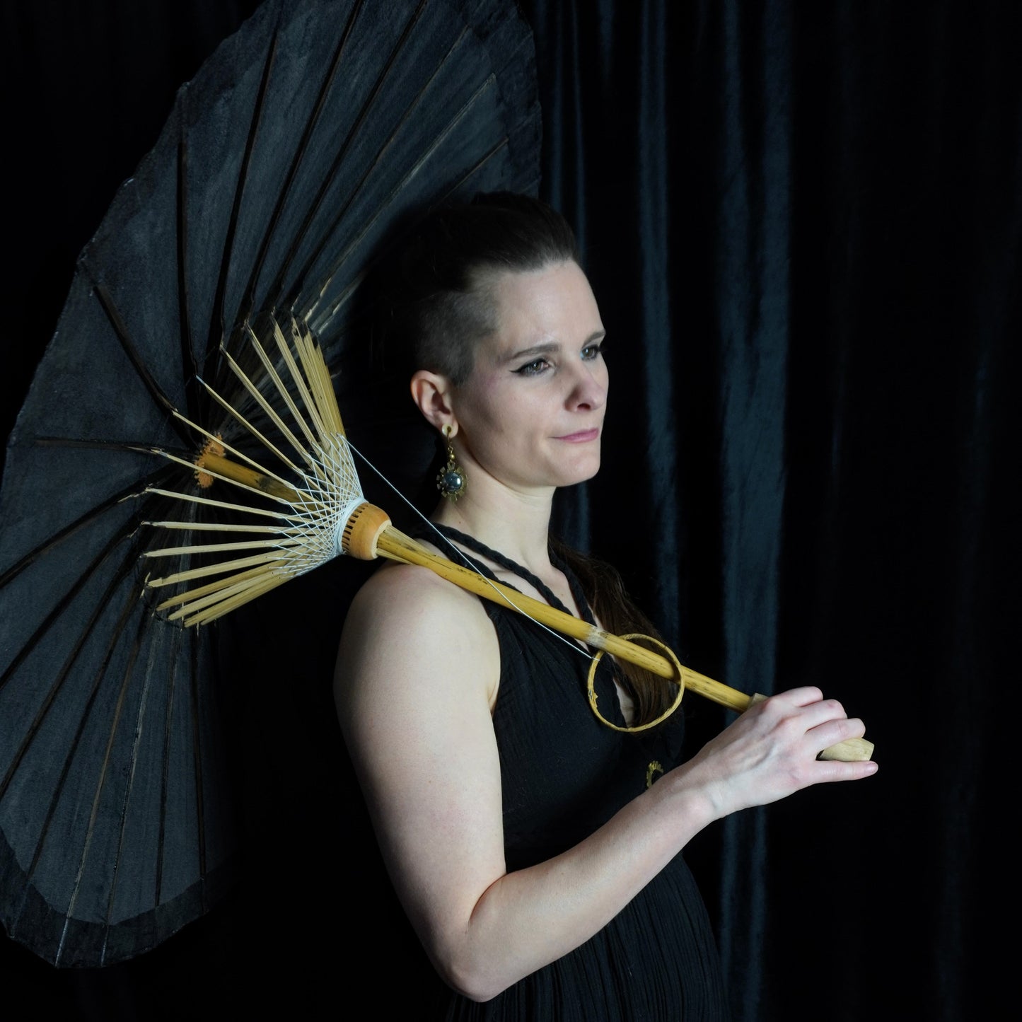 Woman holding a black umbrella against a dark background