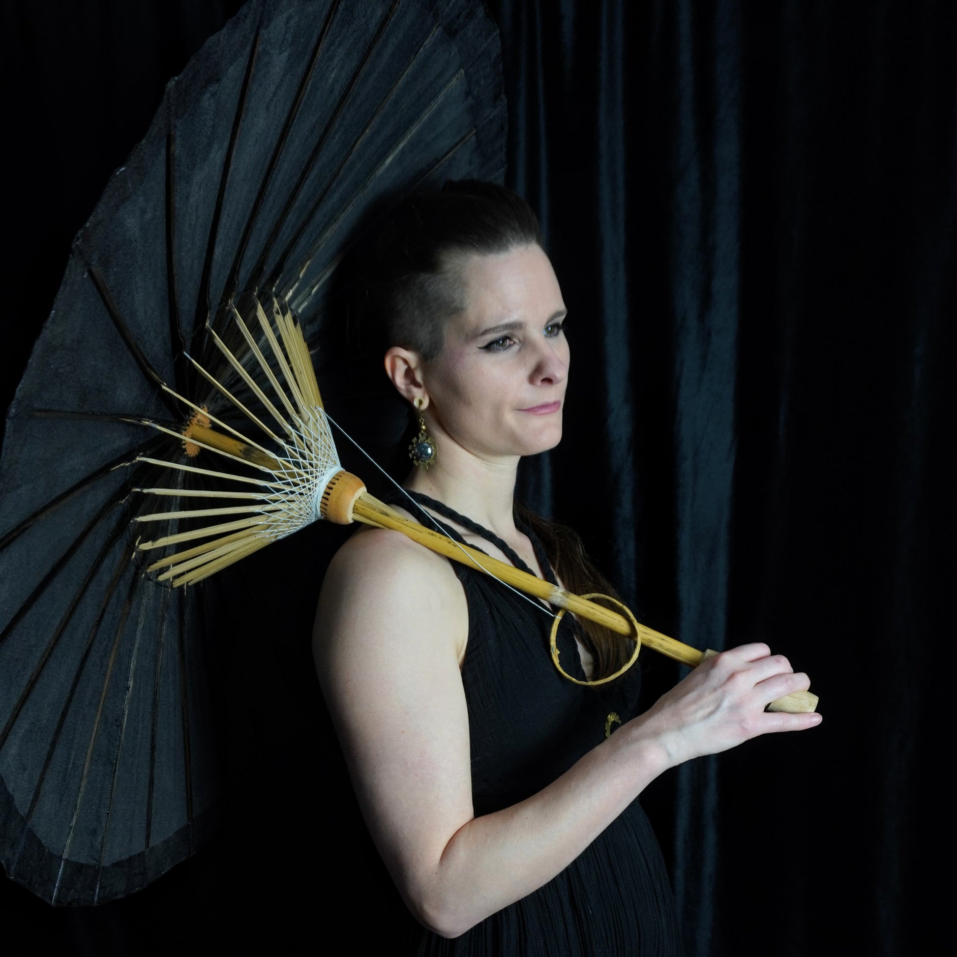 Woman holding a black umbrella against a dark background